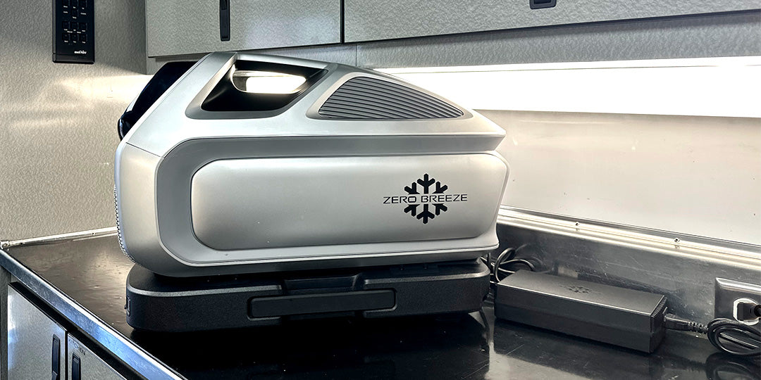 The Mark 3 portable AC is placed on a countertop, plugged into a wall outlet with its power adapter.