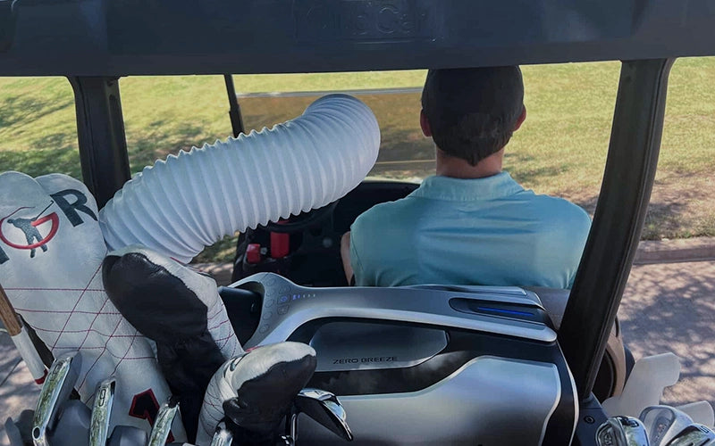 A golfer enjoys a refreshing breeze provided by the Mark 2 portable air conditioner installed in the rear of his golf cart.