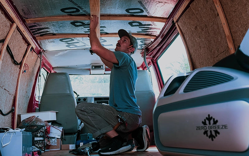 The Mark 3 is placed inside a van, providing cooling comfort to a person working on DIY renovations.