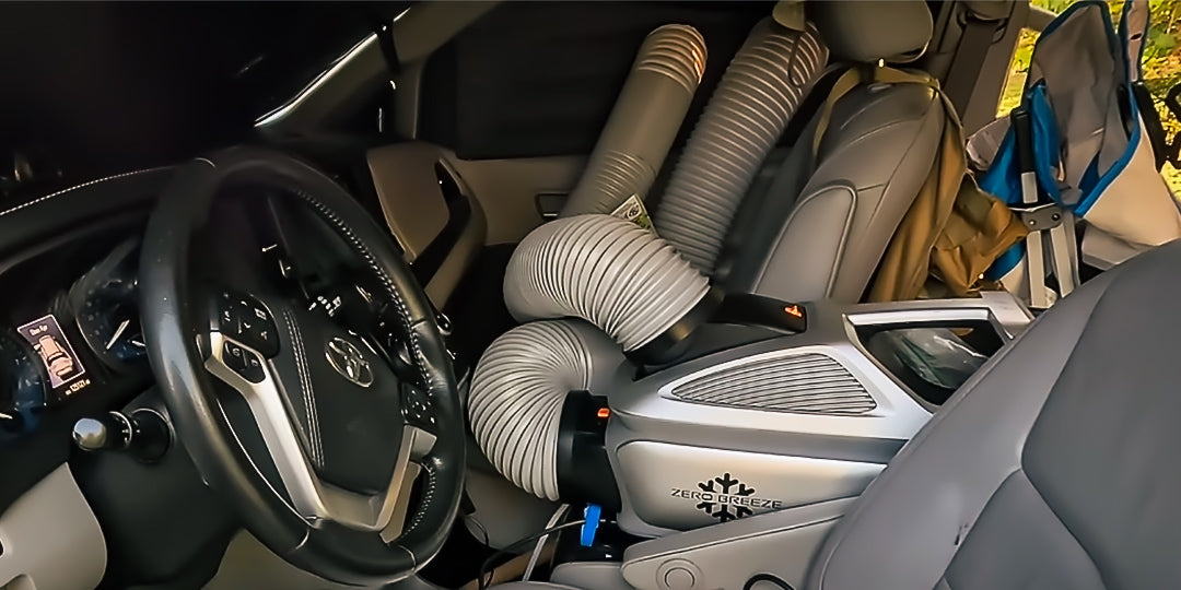 A ZERO BREEZE Mark 3 portable AC is set up inside a car, with both rear ducts routed toward the windows for ventilation, showcasing an in-vehicle cooling solution for road trips or parked rest.
