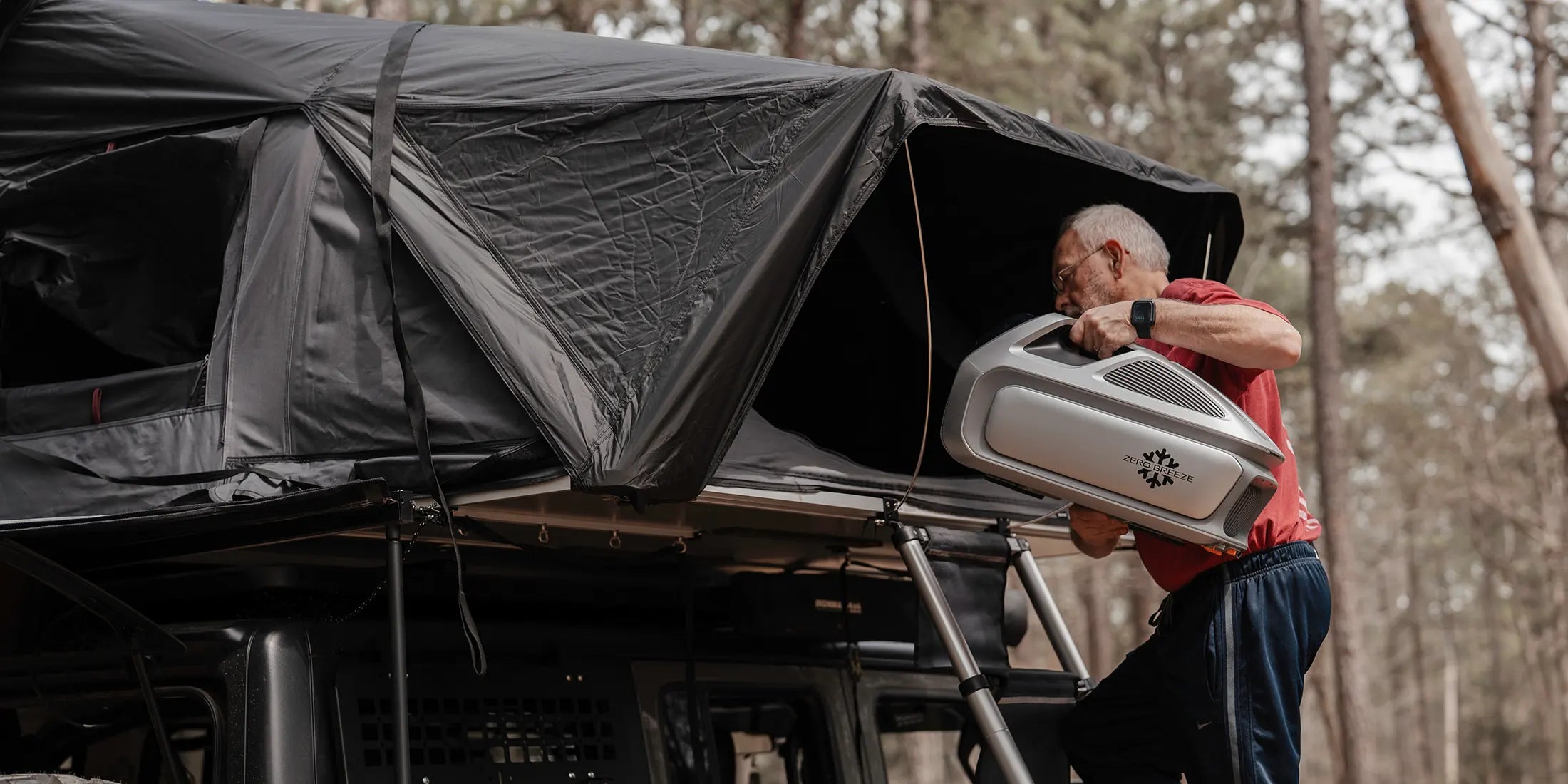 A man is placing the portable Mark 3 into a rooftop tent.
