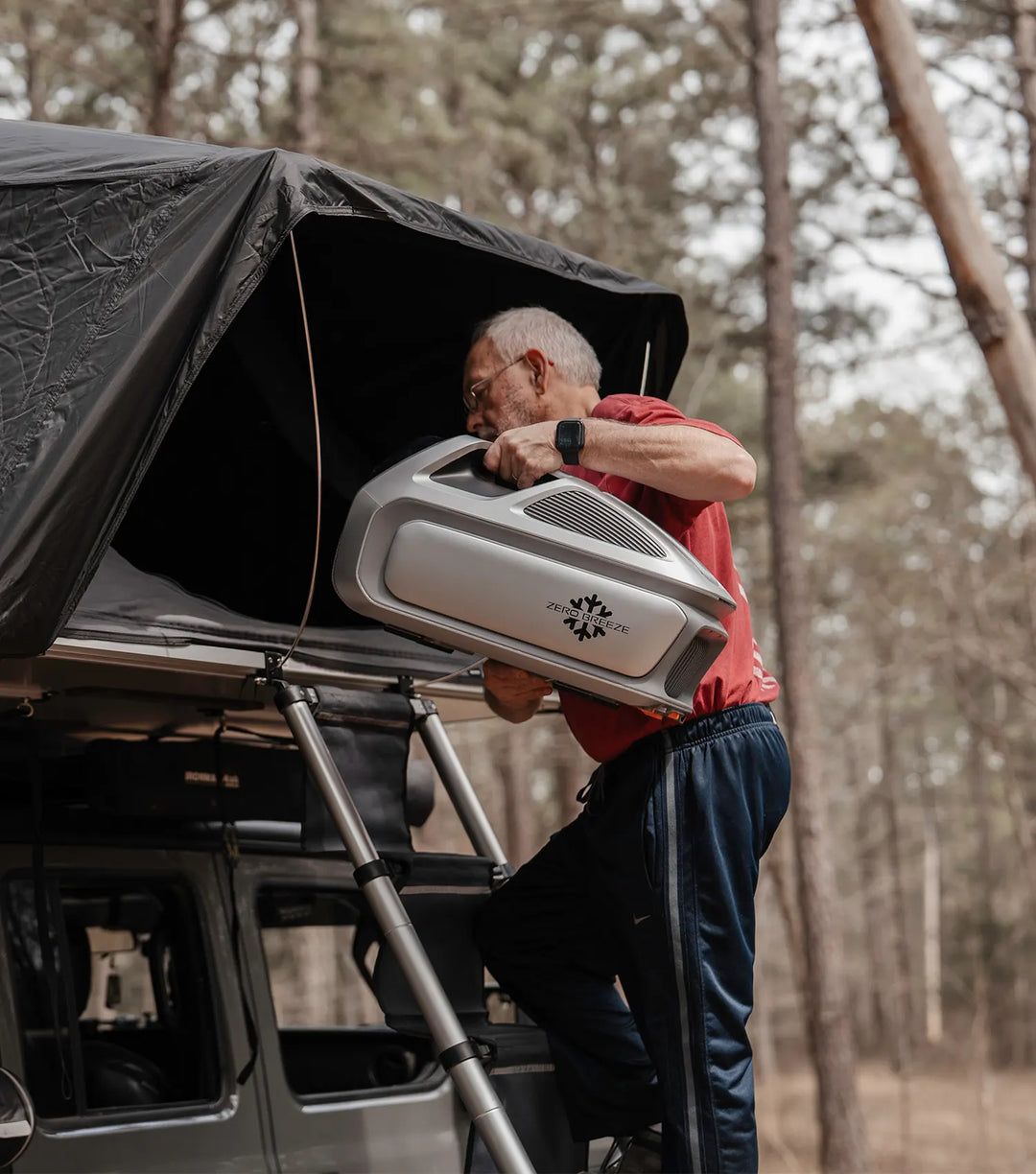 A man is placing the portable Mark 3 into a rooftop tent.