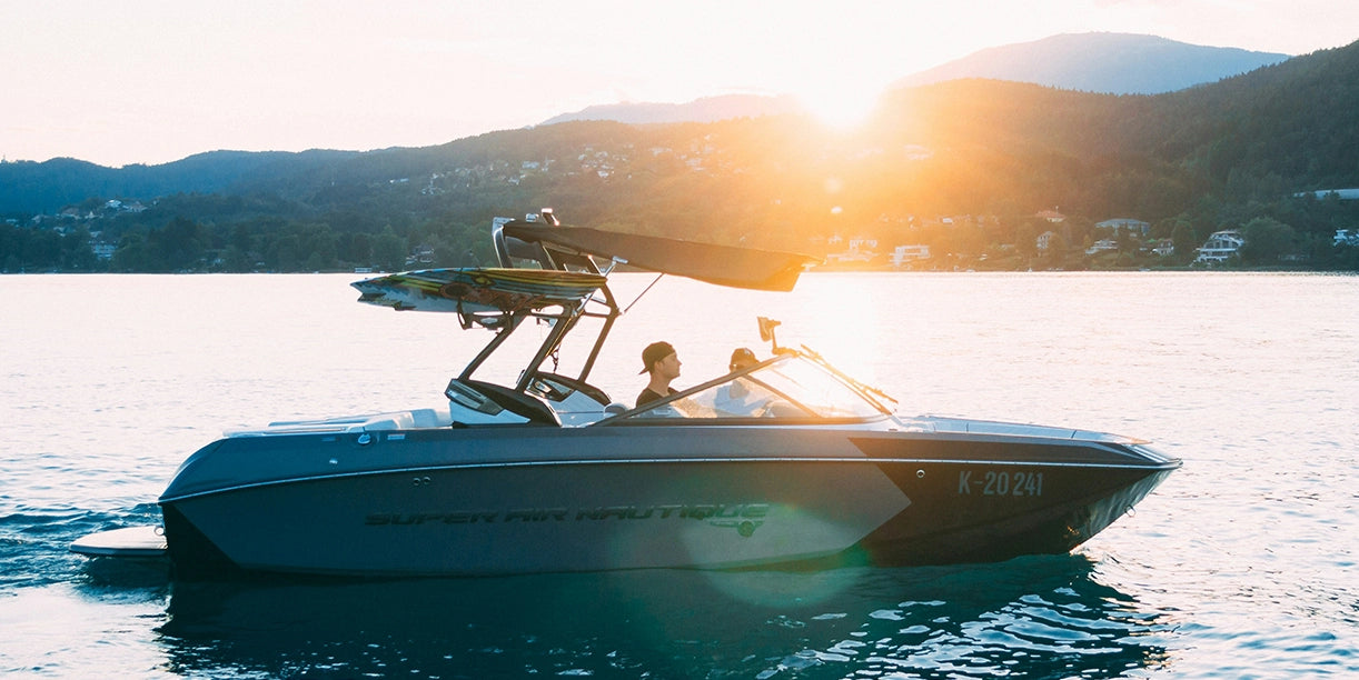 Two men are driving a boat on the sea at sunset, enjoying the serene atmosphere.
